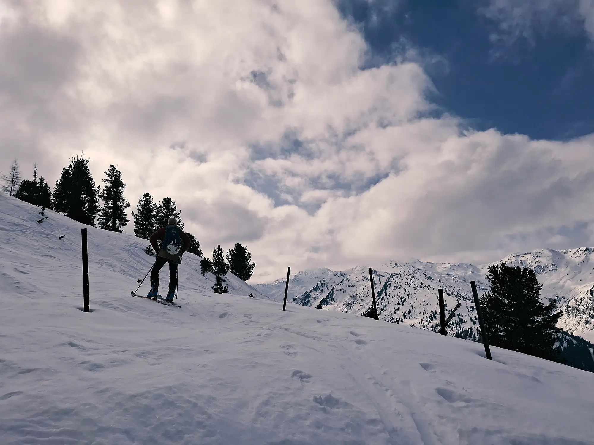 Verschneite Berglandschaft. Ein Skitourengeher schaut auf eine Bergkette.